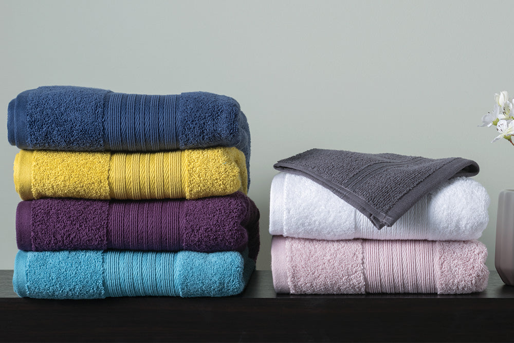 Range of coloured towels folded neatly on a sideboard