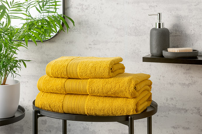 ochre yellow folded towels on a black metal table in a bathroom