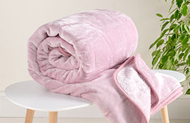 Hamilton McBride pink cosy throw rolled up neatly on a white coffee table