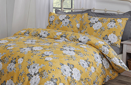 Hamilton McBride yellow floral double bedspread on a double bed with grey bedding underneath